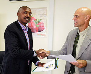 Ernest Ruzindaza (L) exchange documents with Jan Delbaere yesterday. The New Times / Timothy Kisambira.