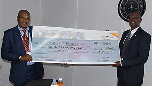 George Githae handing over the Rwf5m dummy cheque to Edward Kalisa, Permanent Secretary in the Ministry of Sports. The New Times/Courtesy.