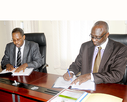 Johnston Businge (R) and Jean Marie Vianney Hitimana sign documents at the handover ceremony. The New Times / John Mbanda.