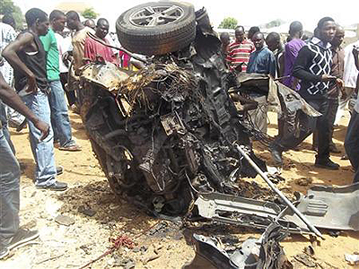 People stand by the wreckage from a car bomb explosion at a church in Yelwa on the outskirts of the northern Nigerian city of Bauchi.  Net photo.