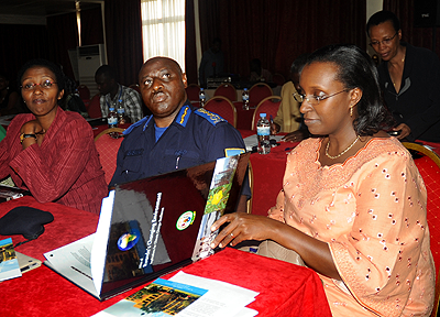 Permanent Secretary in the Ministry of Natural Resources Caroline Kayonga (R) reads through the environment Atlas as other participants who included Inspector General of Police Emmanuel Gasana follow a power point presentation at the launch of the book. T