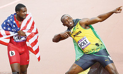 American bronze medallist Justin Gatlin (left) can only look on with envy as Jamaicau2019s Usain Bolt (right) rewrites Olympic history. Net photo.