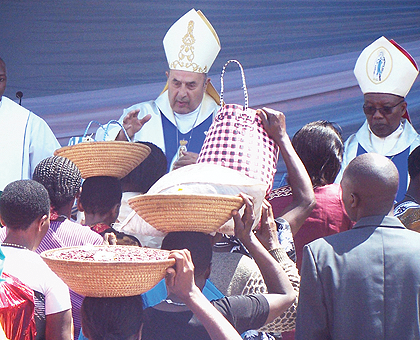 Bishop Maurice Bitz, the Superior of Congregation des Chanoines de Saint Victor Worldwide, from France, and Bishop Philippe Rukamba of Butare Diocese receive offerings from Ugandan pilgrims in Kibeho yesterday. The New Times / JP Bucyensenge.