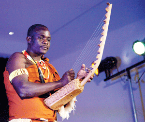 A member of Ndere Troupe playing an Adungu.