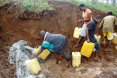 Children take advantage of a roadside broken pipe to get water.  The New Times / John Mbanda.