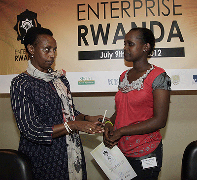 Marie Christine Gasingirwa(Left) , the Director General for Technology and Research in the Ministry of Education, congratulating Jessie Gakwandi, one of the winners. The New Times / T. Kisambira.