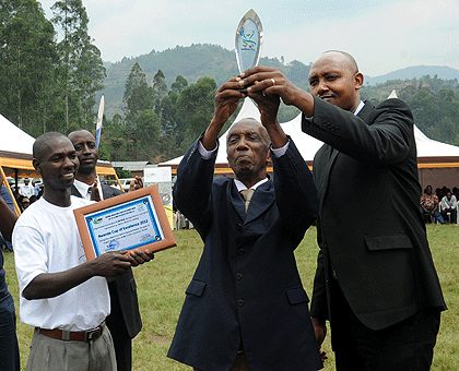 Alexis Gahizi (2nd right) of Gitesi in Karongi District who won the first prize being awarded by Permanent Secretary in the Ministry of Agriculture Ernest Ruzindaza. The New Times / John Mbanda.