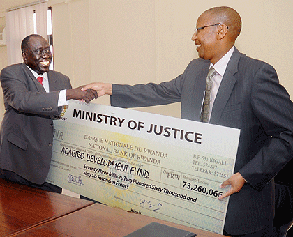 Justice minister Tharcise Karugarama (L) hands over a 73 million franc cheque to Finance minister John Rwangombwa, as staff contribution to the Agaciro Development Fund. The New Times/J. Mbanda.