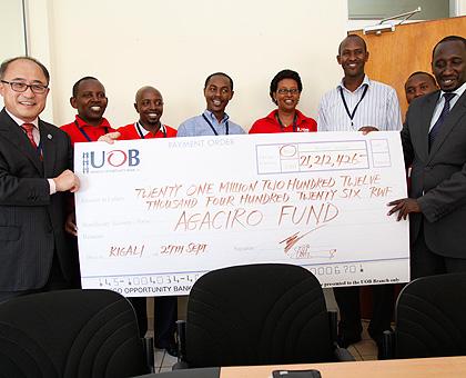 UOBu2019s Jeffrey Lee (L) hands over the dummy cheque to Ronald Nkusi of the Ministry of Finance.  The Sunday Times / P. Mbabazi