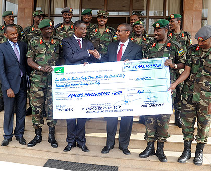 Defence Minister Gen. James Kabarebe (3rd left), flanked by RDF senior officers, hands a cheque,  meant for Agaciro Development Fund, to Finance Minister John Rwangombwa yesterday. The New Times / J. Mbanda.