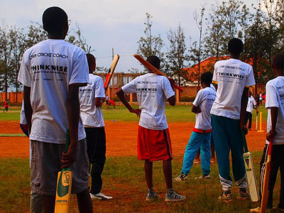 School children getting cricket playing tips from CWB volunteers at Kicukiro Oval. The New Times / Courtesy.