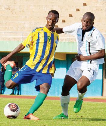 Botswanau2019s Kebue Thato (no.21), one of the alleged overage players, closes in on junior wasps' striker Fiston Nkinzingabo during Saturday's qualifier at Amahoro stadium, in Kigali. The New Times / T. Kisambira.