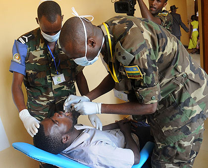A Rwandan soldier and his Burundian counterpart (L) handling a dental case at Gashora Health Centre. The New Times / John Mbanda.