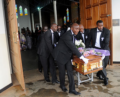 Mourners roll the casket out of church yesterday. The New Times / John Mbanda.