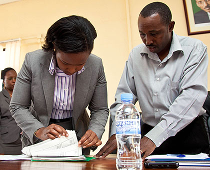 Clare Akamanzi, the acting CEO of RDB (L),counting the land titles as  Augustine Emmanuel Mukunzi  the deputy land register  looks on. The New Times / T.Kisambira.