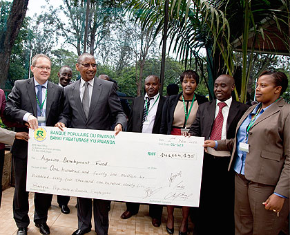 Minister of Finance John Rwangombwa in a group photo with Banque Populaire staff after receiving the dummy cheque.  The New Times / T.Kisambira.