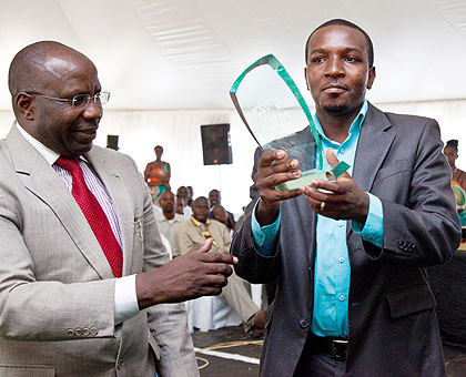 Prime Minister Dr.Pierre Damien Habumuremyi hands over a trophy of the best exhibitor to Frederic Mutangana principal of IPRC west Kibuye. The New Times / T.Kisambira.