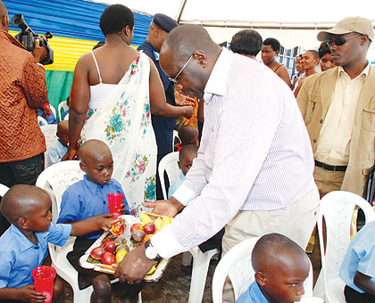 Premier Pierre Damien Habumuremyi feeds a child at the closing of the Family Campaign. The New Times / Courtesy.