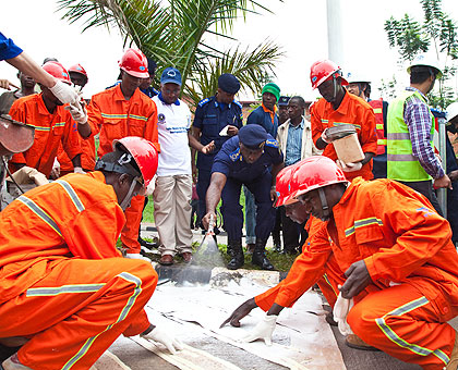 IGP Emmanuel Gasana(C) sprays paint to mark the beginning of Road safety week at Kimihurura as State Minister in charge of Transport, Alex Nzahabwanimana, looks on. The New Times 
