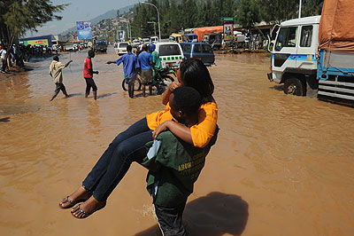 A woman is carried cross a flooded Nyabugogo road last year. The Ministry of Disaster Management and Refugee Affairs has launched an initiative to simplify the reporting of disasters across the country. The New Times / File.