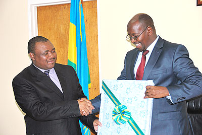 Local Government Minister James Musoni (R) hands a gift to his counterpart from Lesotho, Mothetjoa Metsing, during their meeting at the former's office on Monday. The New Times/Courtesy.