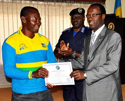 The Mayor of the City of Kigali, Fidele Ndayisaba, gives a certificate to one of the course participants as IGP Emmanuel Gasana looks on. The New Times / Courtesy.