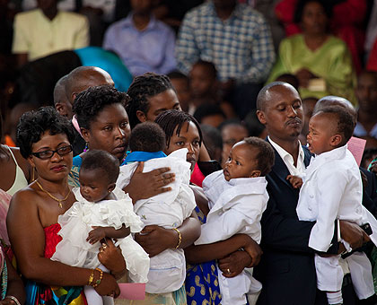 Parents  carrying their babies during baptism at St Michael Cathedral yesterday. This was part of the events organised for Christmas Day. The New Times / Timothy Kisambira.