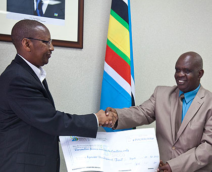 Finance minister John Rwangombwa receives the dummy cheque from Jean Marie Vianney Nzagahimana, Board Chairman, Umwalimu-Sacco (R), in Kigali yesterday. The New Times / T. Kisambira.