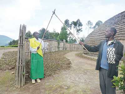 Rick Masubuko (L) and Vincent Sikubwabo  show how visitors were welcomed in the Ancient times at the Kitabi Cultural Village. 