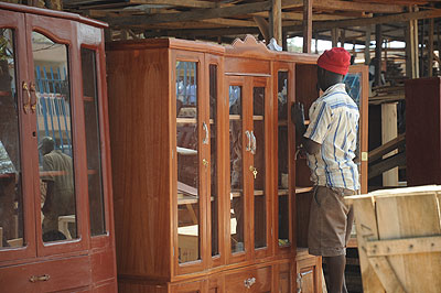 A carpenter  dusting a sideboard. Furniture business is the main activity in town.