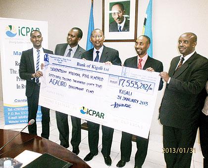 The Minister of Finance and iCPAR staff hold the dummy cheque.