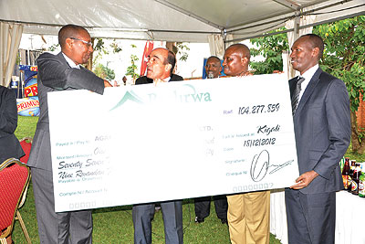 Finance minister Rwangombwa (left) receives the contribution dummy cheque from Bralirwa MD, Jonathan Hall (centre) on Wednesday. The New Times/Ben Gasore .