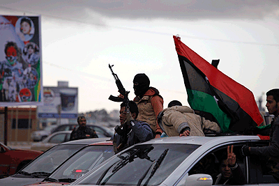 A Libyan masked gunman celebrates on the roof of a vehicle on the early morning of the second anniversary of the revolution that ousted Muammar Gadhafi, in Benghazi, Libya, Sunday.  Ne....