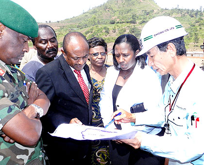 Brig. Gen. Dan Gapfizi (L), Massawa (in black suit) and Uwamariya listen to Eng. Kameda explain how the construction project is panning during a tour of the border facility at the week....