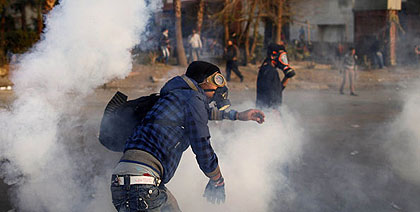 An Egyptian protester throws back tear gas canisters during clashes with riot police near Tahrir Square in Cairo on March 9, 2013. A court verdict over deadly football violence spar....