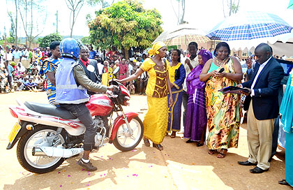Mukasonga (2nd R) and AEEu2019s Phanuel Sindayiheba (R) hand over a motorcycle to a beneficiary.  The New Times/  Laurent Kamana.