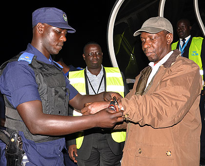    Head of the Genocide Fugitives Tracking Unit, John Bosco Siboyintore (C) watches as Bandora is handcuffed upon arrival at the Kigali International Airport on Sunday.   The New Times....