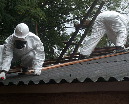 Experts remove asbestos sheets from a roof last year. Inset is a house with asbestos. The New Times/ File
