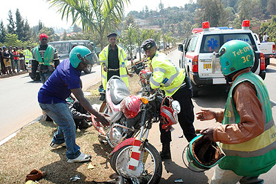 Traffic Police officers help a taxi-moto accident victim off the road recently. The New Times/ T. Kisambira.