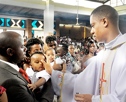 HOLY RECRUITMENT: Fr. Jean Claude Muvandimwe anoints a baby during a Baptism session at St. Michel Cathedral yesterday. 