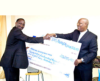 Caritas-Rwandau2019s Thaddu00e9e Ntihinyurwa (R), also the archbishop of Kigali Diocese, hands a dummy cheque to Ronald Nkusi, the director of External Finance Unit at the Ministry of Finan....