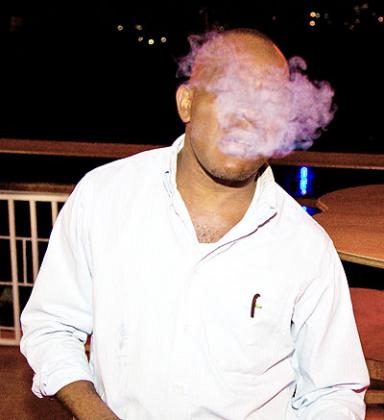 A man is engulfed in cigarette fumes in a public place. The New Times/ Timothy Kisambira.