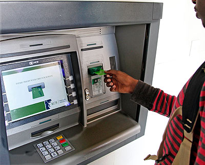 A bank client uses an automated card. The New Times / T. Kisambira.