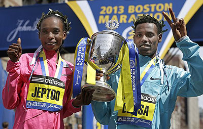 Rita Jeptoo of Kenya and Lelisa Desisa of Ethiopia pose with a trophy at the finish line after winning the women's and men's divisions of the 2013 Boston Marathon. Net photo.