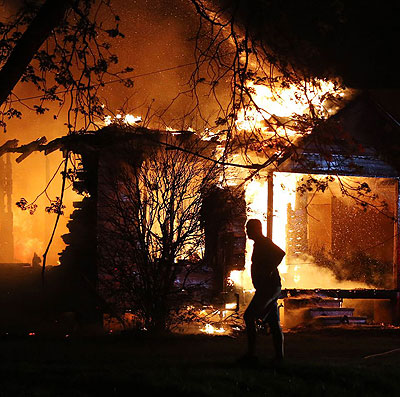 A man is silhouetted by blaze ravaging a home in the vicinity of the Waco blast zone. There were no immediate official comments on what may have sparked the fire or what led to the mas....