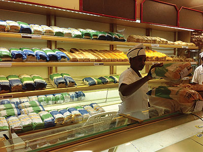 A worker packing bread at a store in town. The prices of bread are bound to rise as bakers try to cover operations costs. The New Times / Peterson Tumwebaze