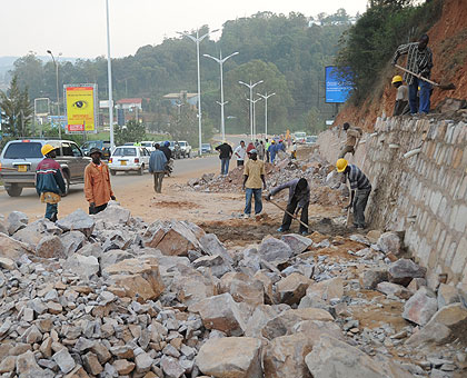 Road construction workers fix streetside drainage and pedestrian walkways in Kigali.   The New Times/ Timothy Kisambira.