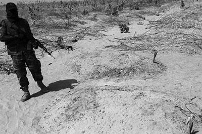 A soldier walks past graves of victims of clashes between Islamists and soldiers in Baga in Nigeria. Net photo.