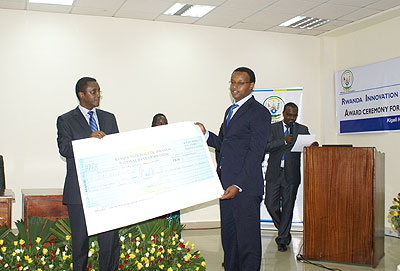 Education Minister Biruta(L) handing over a dummy cheque to Rutagambwa. The New Times/ Laurent Kamana