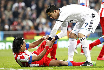 Cristiano Ronaldo helps Atletico striker Falcoa off the ground during the league match at Santiago Bernabeu. Net photo.